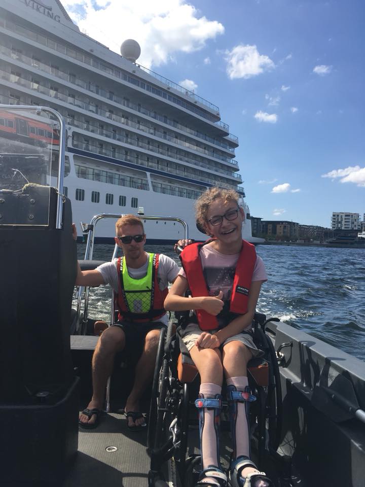 kørestols bruger i båd, med pædagog i baggrunden